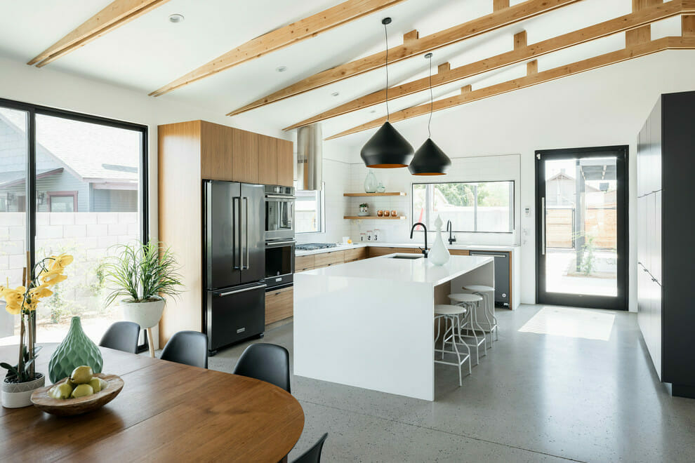 Modern-white-kitchen-design-with-black-pendants-and-white-waterfall-countertop-and-subway-tiles