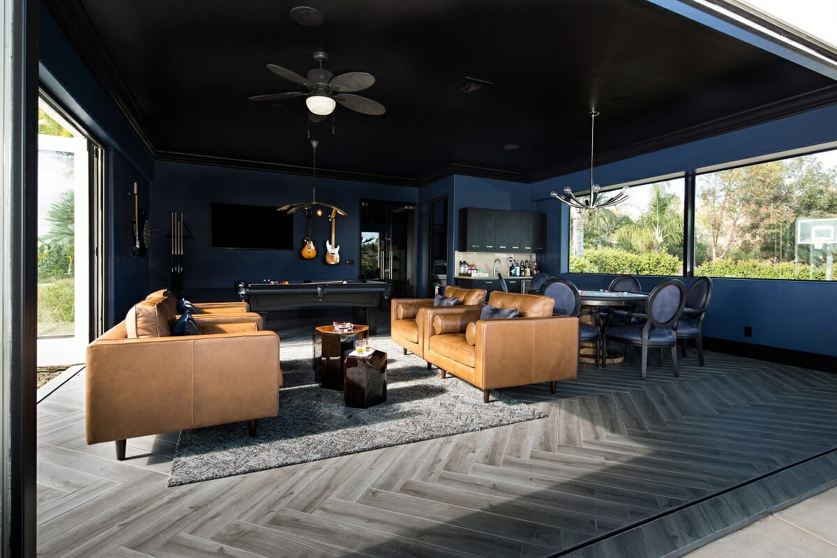 Basement multipurpose room design in a moody blue with gaming and a bar lounge
