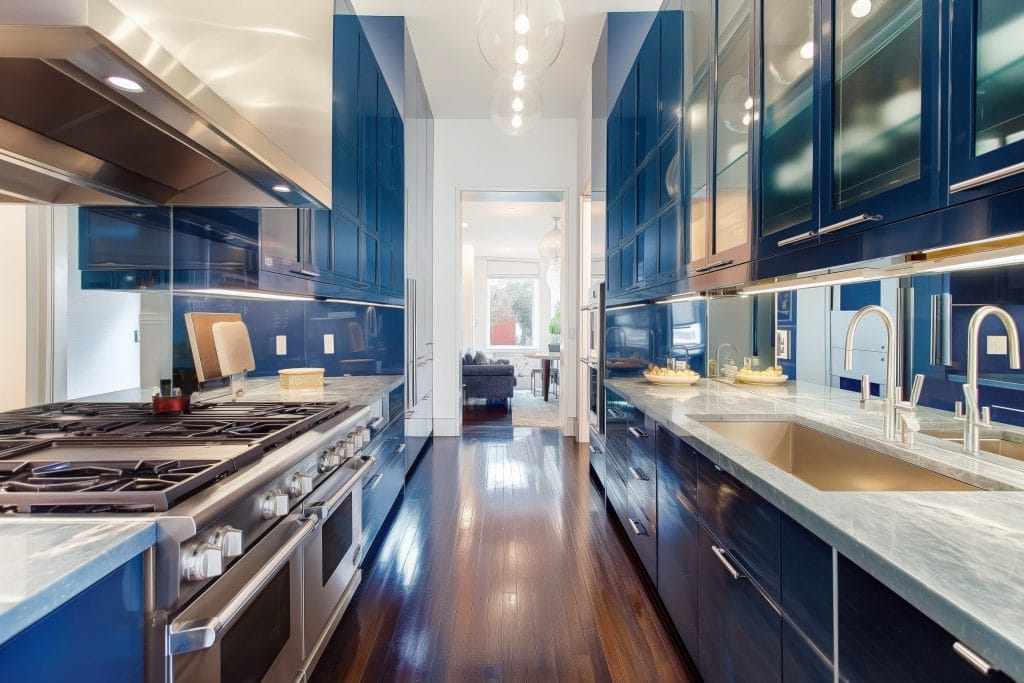 Galley kitchen design with a mirror backsplash by Decorilla