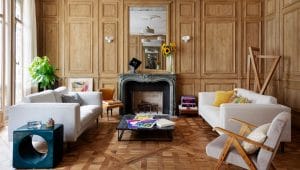 Wood-paneled living room with white sofas, colorful accent chairs, a marble fireplace and parquet flooring